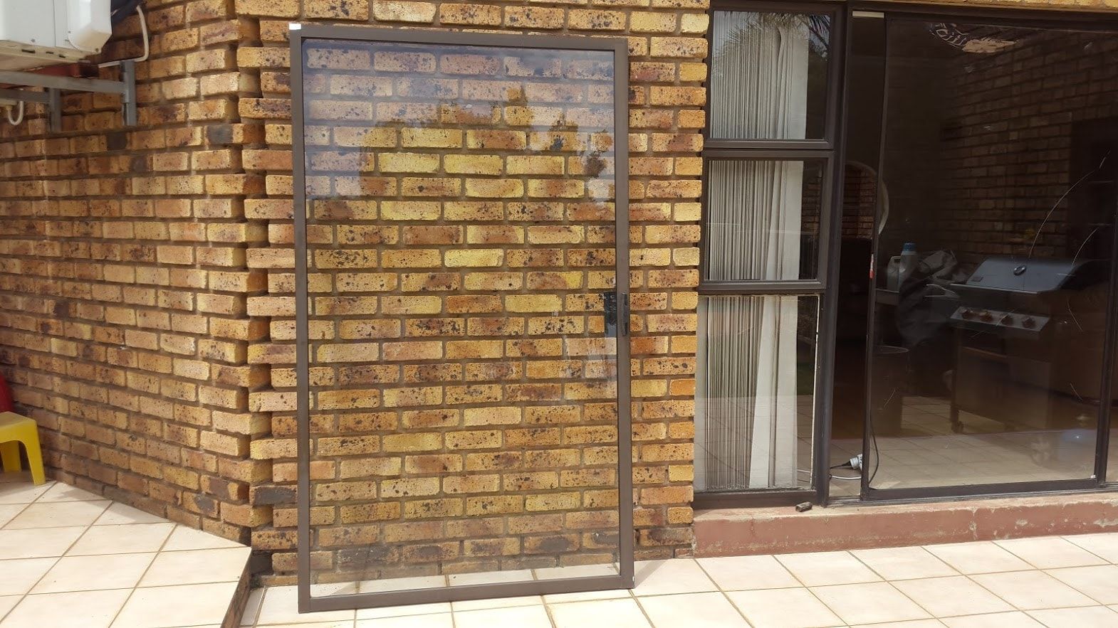 Sliding door panel standing against a face-brick wall beside the open doorway